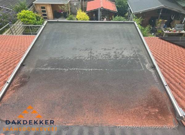 Verouderd plat dak met slijtage tussen schuine daken in Raamsdonksveer Verouderd plat dak met slijtage tussen schuine daken in Raamsdonksveer