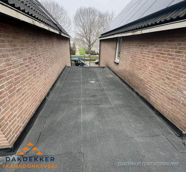 Plat dak met bitumen dakbedekking tussen bakstenen muren in Raamsdonksveer Plat dak met bitumen dakbedekking tussen bakstenen muren in Raamsdonksveer